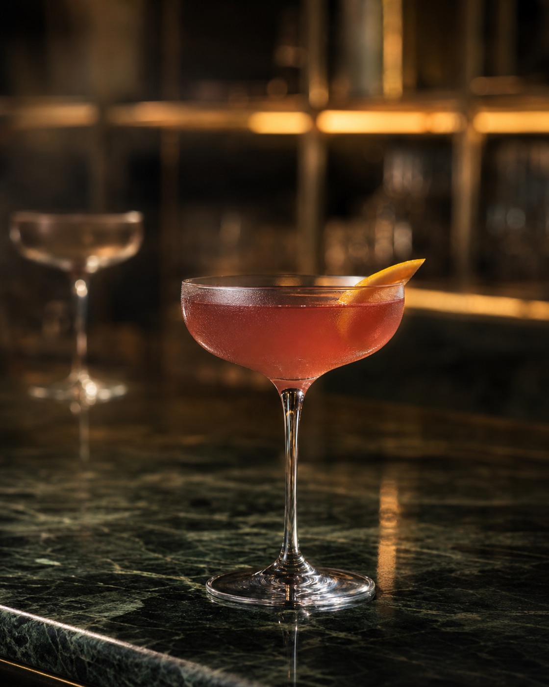 Atmospheric concept of a raspberry-toned cocktail on a forest-green marble bar